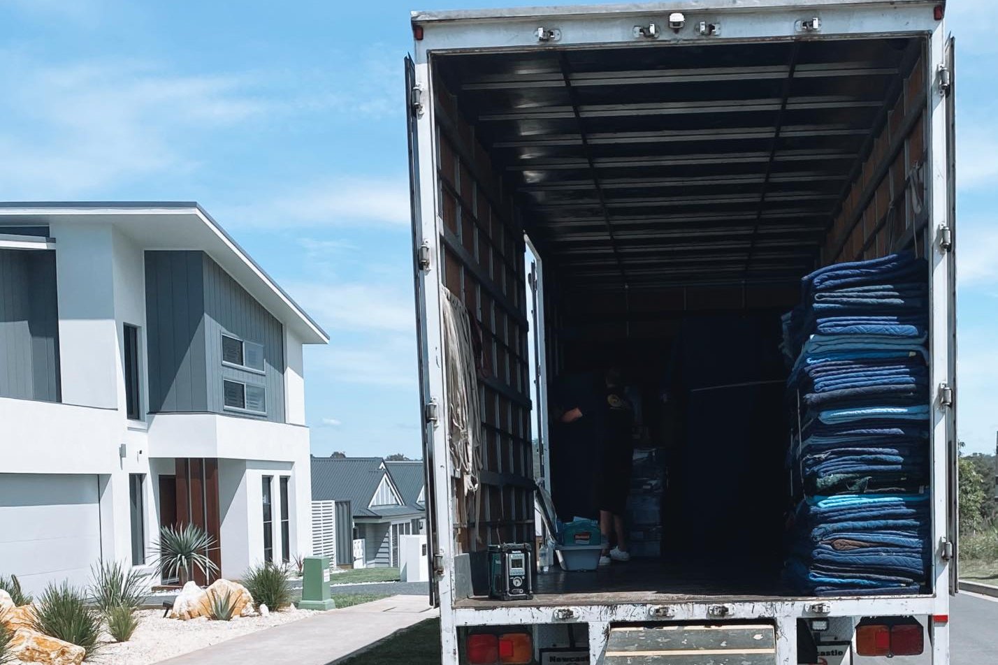 Easy Choice Removals truck loaded with padded moving blankets and boxes, ramp extended to the driveway